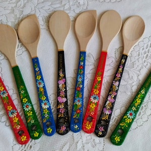May include: Wooden spoons with painted handles. The handles are decorated with floral patterns in various colors, including red, blue, green, and black. Some handles have the word "UKRAINE" painted on them.