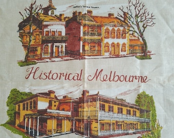 Puede incluir: Un paño de cocina vintage con fondo beige e ilustraciones de edificios históricos en Melbourne, Australia. El texto "Historical Melbourne" está impreso en letras cursivas marrones. Los edificios están representados en varios tonos de marrón, amarillo y rojo.