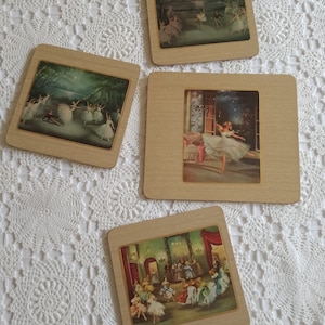 Op de afbeelding: Vier houten onderzetters met afbeeldingen van ballerina's in verschillende poses. De onderzetters hebben een lichtbruine houten lijst met een gouden rand en een witte achtergrond. De afbeeldingen zijn in kleur gedrukt en tonen de ballerina's in verschillende stadia van een uitvoering.