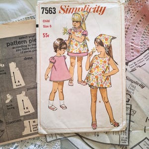 Könnte beinhalten: Vintage Simplicity Schnittmuster für ein Kinderkleid, Größe 6. Das Cover zeigt Illustrationen von Kindern in Kleidern und Bloomers. Das Schnittmustercover ist gealtert mit Gebrauchsspuren, und der Preis ist mit 55 Cent angegeben.