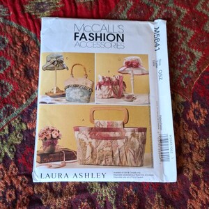 May include: A McCall's Fashion Accessories sewing pattern envelope, model M5641, featuring Laura Ashley designs. The front displays illustrations of various hats and handbags, including a large tote with a wooden handle and floral fabric patterns.