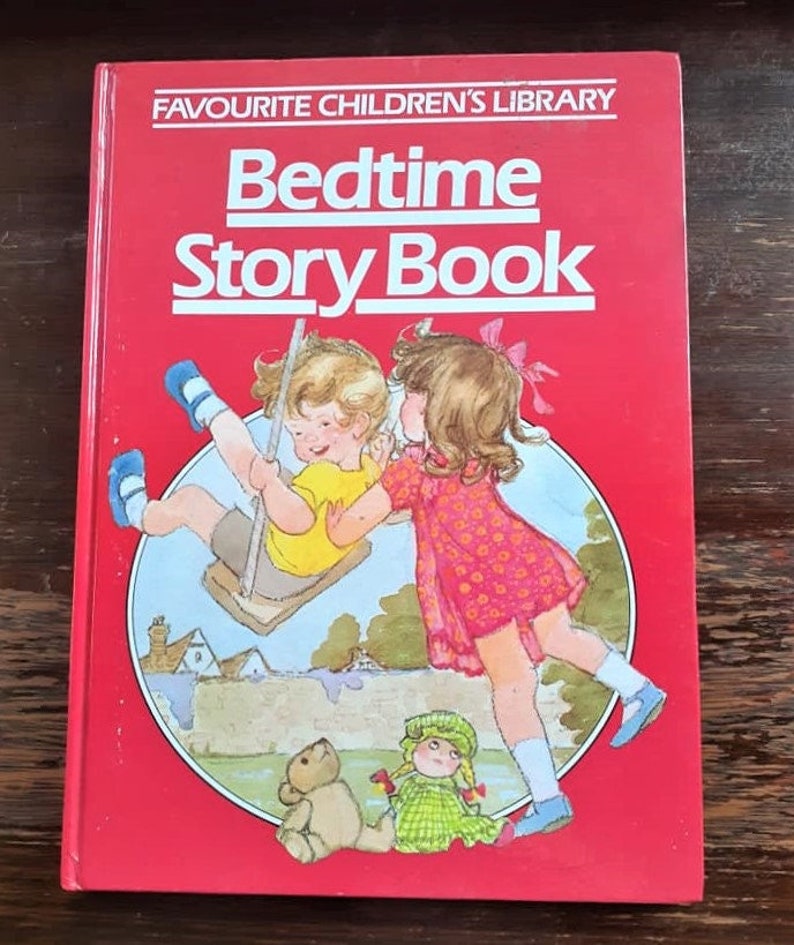 May include: A red book with the title "Favourite Children's Library Bedtime Story Book" in white text. The cover features an illustration of two children, a boy on a swing and a girl standing next to him, with a teddy bear and a doll in the foreground.