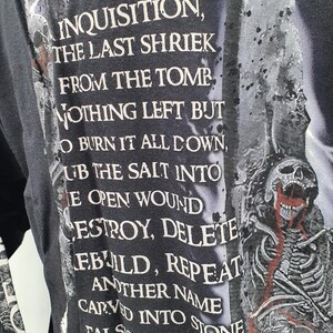 May include: Black long-sleeve shirt with white text that reads "Welcome all to the new inquisition, the last shriek from the tomb. Nothing left but to burn it all down, rub the salt into the open wound. Destroy, delete, rebuild, repeat. Another name carved into stone falsely then pretend, as we cut the cord and wait for the end."