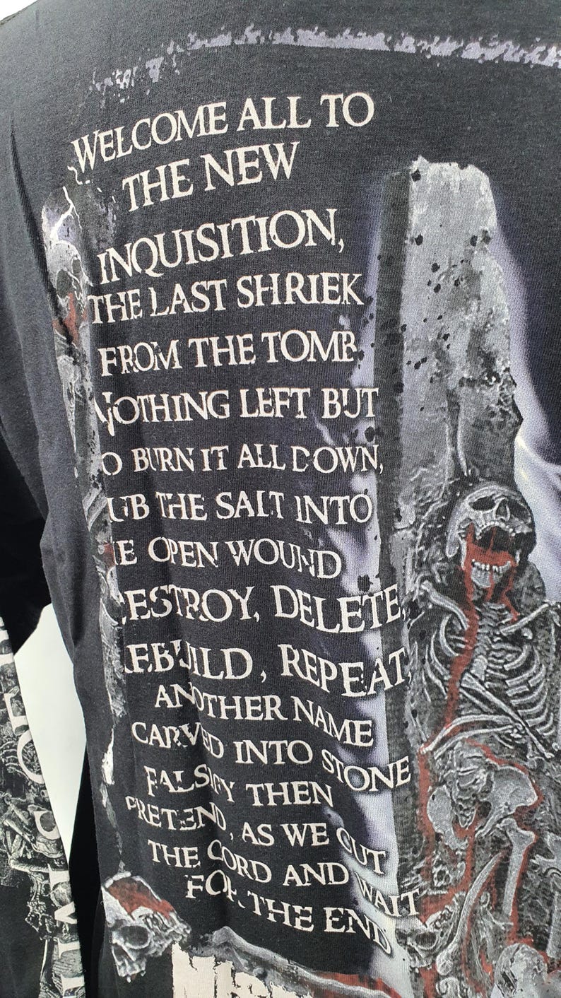 May include: Black long-sleeve shirt with white text that reads "Welcome all to the new inquisition, the last shriek from the tomb. Nothing left but to burn it all down, rub the salt into the open wound. Destroy, delete, rebuild, repeat. Another name carved into stone falsely then pretend, as we cut the cord and wait for the end."