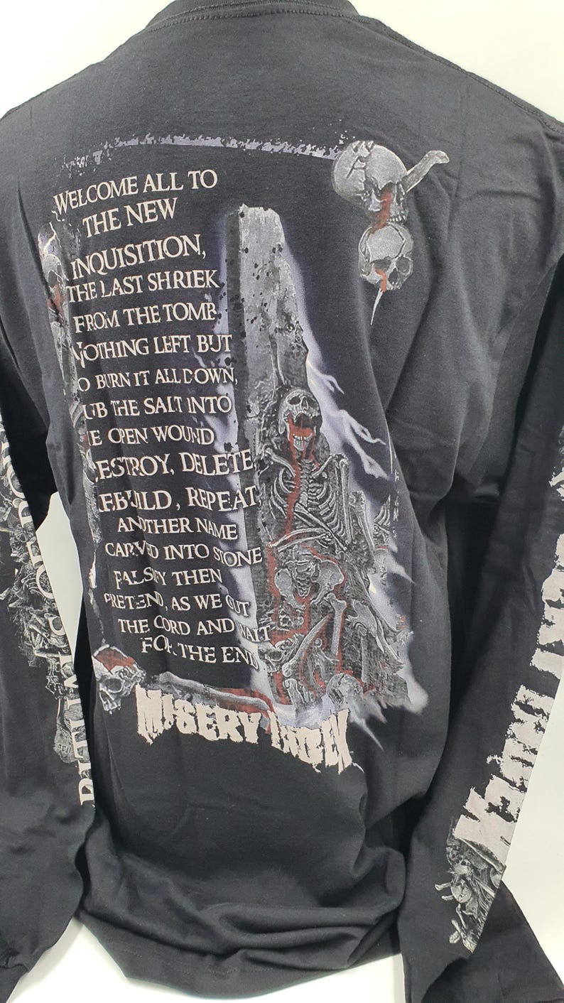 May include: Black long-sleeve t-shirt with a graphic print of a skeleton holding a skull. The text "WELCOME ALL TO THE NEW INQUISITION, THE LAST SHRIEK FROM THE TOMB NOTHING LEFT BUT O BURN IT ALL DOWN, UB THE SALT INTO THE OPEN WOUND DESTROY, DELETE REBUILD, REPEAT ANOTHER NAME CARVED INTO STONE FALSEY THEN PRETEND, AS WE CUT THE CORD AND WAIT FOR THE END MISERY INDEX" is printed on the back of the shirt.
