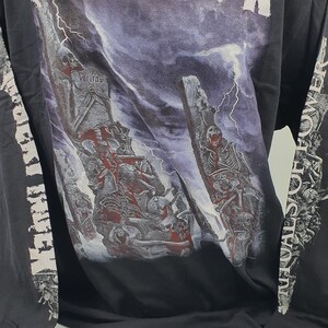 May include: Black long-sleeve t-shirt with a graphic print of a band called "Misery Index". The graphic features a skeletal figure and a stormy sky. The sleeves have the band's name printed on them in white.