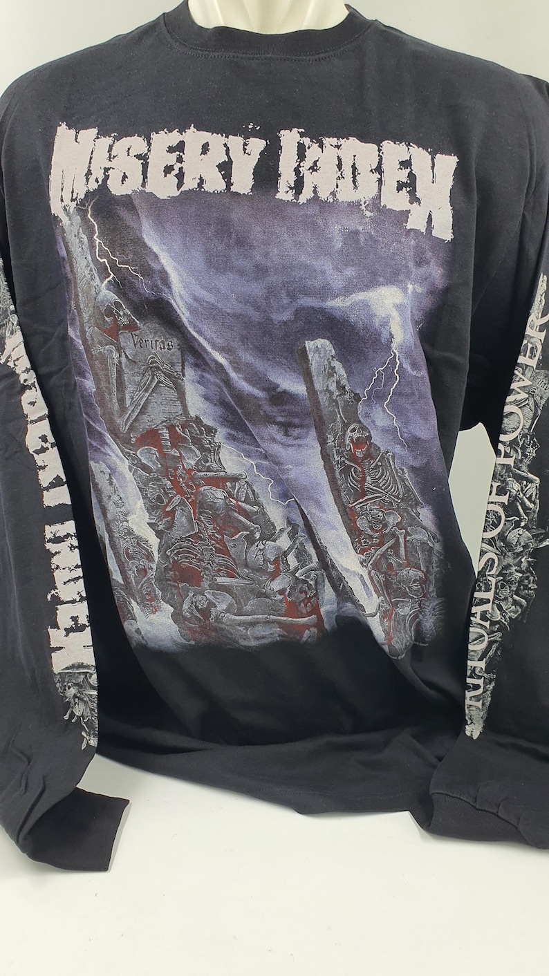 May include: Black long-sleeve t-shirt with a graphic print of a band called "Misery Index". The graphic features a skeletal figure and a stormy sky. The sleeves have the band's name printed on them in white.