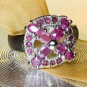 May include: A silver ring with a cluster of pink ruby gemstones set in a floral design.