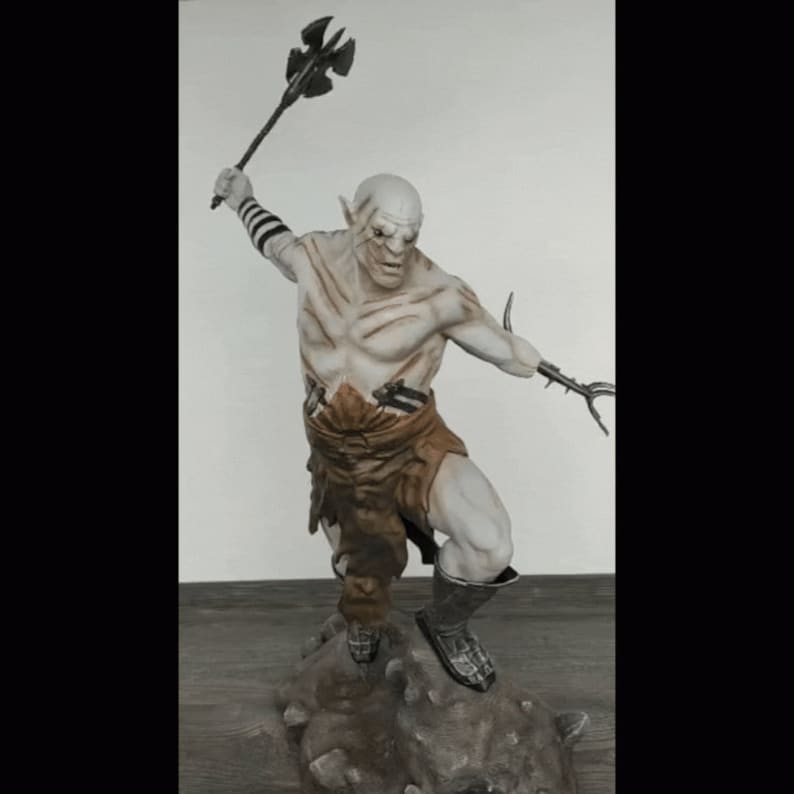 K&ouml;nnte beinhalten: Eine wei&szlig;e Orc-Figur mit einem braunen Lendenschurz und einer Axt aus Metall, die auf einem felsigen Sockel steht.
