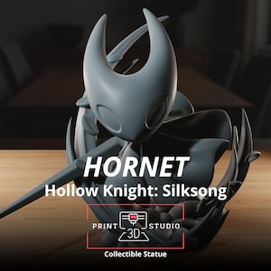 Puede incluir: Una estatua coleccionable gris del personaje Hornet de Hollow Knight: Silksong. La estatua presenta un diseño detallado con una cabeza con cuernos y una capa fluida. Los textos "HORNET" y "Hollow Knight: Silksong" son visibles. La base de la estatua es negra.