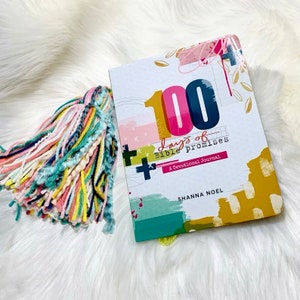 May include: A white journal with a colourful abstract design and the text "100 Days of Bible Promises A Devotional Journal" and "SHANNA NOEL".