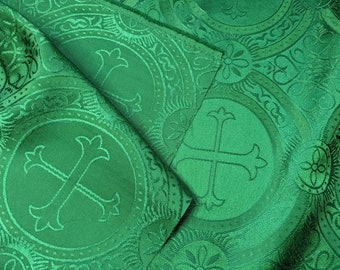 Op de afbeelding: Groene stof met een herhalend patroon van sierlijke cirkels met kruisen. De stof heeft een subtiele glans en een textuur.