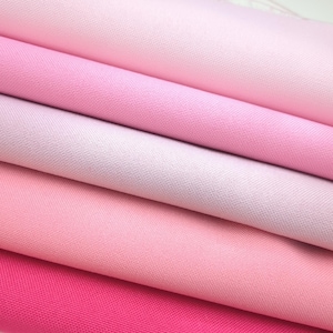 May include: A stack of pink fabric swatches in varying shades, from light blush to vibrant fuchsia. The fabric has a fine weave, and the layers are neatly arranged, showcasing the range of pink hues.