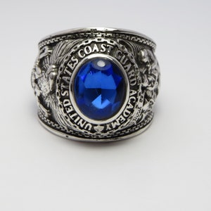 Peut inclure: Une bague en argent avec une pierre précieuse bleue et l'inscription "UNITED STATES COAST GUARD ACADEMY".