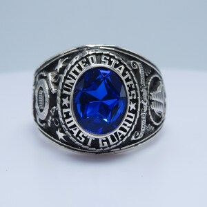 Peut inclure: Une bague en argent avec une pierre précieuse bleue et l'inscription "United States Coast Guard".