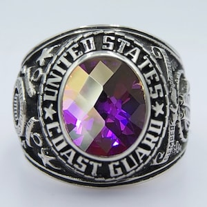 May include: A silver ring with a purple gemstone and the inscription "United States Coast Guard" around the band.