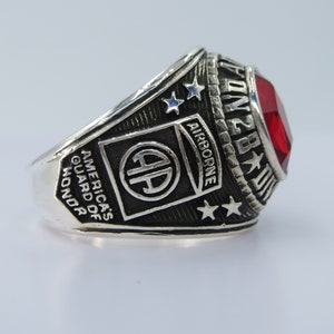 May include: Silver ring with a red stone, the inscription "101st Airborne" and the words "America's Guard of Honor".