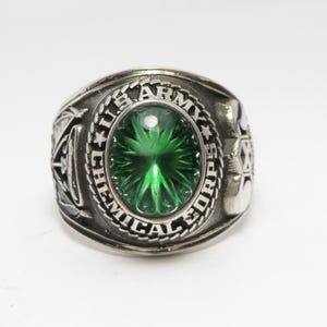 Op de afbeelding: Een zilveren ring met een groene edelsteen en de inscriptie "U.S. ARMY CHEMICAL CORPS".