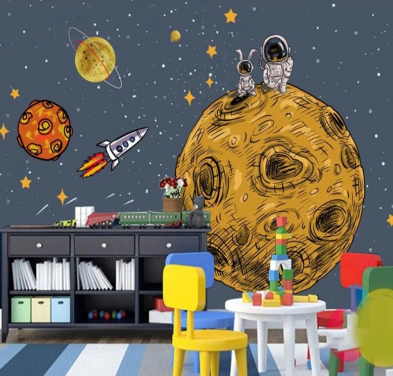 K&ouml;nnte beinhalten: Ein gelber und brauner Cartoon-Planet mit zwei Astronauten, die oben drauf stehen. Der Planet ist von Sternen und einer Rakete umgeben. Der Hintergrund ist dunkelblau mit wei&szlig;en Sternen.