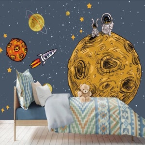 K&ouml;nnte beinhalten: Ein blaues und gelbes Wandbild f&uuml;r ein Kinderzimmer mit Weltraumthema mit einem gro&szlig;en gelben Mond, zwei Astronauten, einer Rakete und Sternen.