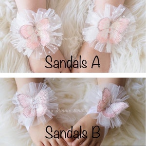 May include: Two pairs of white tulle baby sandals with pink butterfly embellishments. The sandals are labeled "Sandals A" and "Sandals B".