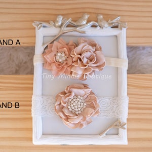 May include: Two peach-colored fabric flower headbands with pearl accents. The headband on top has two flowers, one with a ruffled edge and the other with a more rounded shape. The headband on the bottom has one large flower with a ruffled edge. Both headbands are on a white background with a decorative branch and the text "Tiny Minnie Boutique".