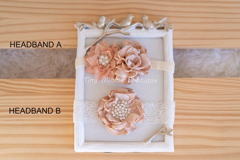 May include: Two peach-colored fabric flower headbands with pearl accents. The headband on top has two flowers, one with a ruffled edge and the other with a more rounded shape. The headband on the bottom has one large flower with a ruffled edge. Both headbands are on a white background with a decorative branch and the text "Tiny Minnie Boutique".