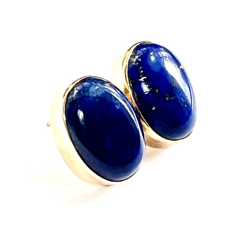 K&ouml;nnte beinhalten: Ein Paar ovale Lapislazuli-Ohrringe, die in Gold gefasst sind.