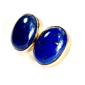 K&ouml;nnte beinhalten: Ein Paar goldene Ohrringe mit ovalen Lapislazuli-Steinen. Die Steine sind tiefblau mit goldenen Einschl&uuml;ssen.