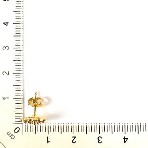以下が含まれることがあります： 円形のデザインの金色のイヤリング。イヤリングは定規で測定されており、直径は約1cmであることがわかります。