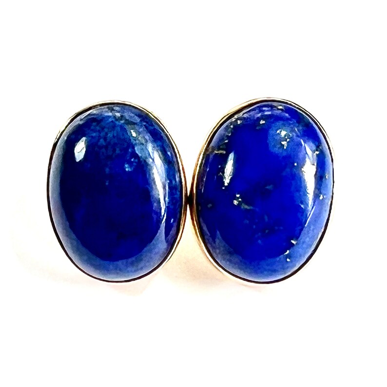 K&ouml;nnte beinhalten: Ein Paar ovale Lapislazuli-Ohrringe mit goldenen Fassungen. Die Ohrringe sind tiefblau mit goldenen Sprenkeln.