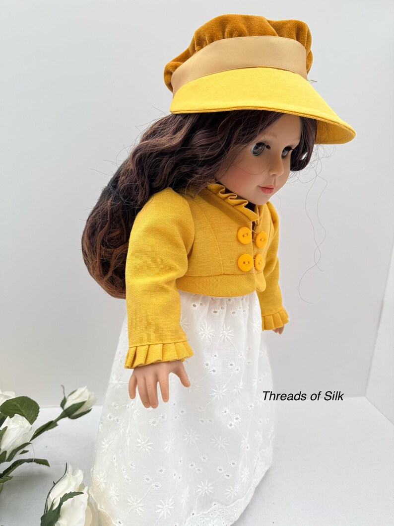 May include: A doll wearing a yellow jacket with round buttons, a white eyelet skirt, and a yellow visor hat with a brown brim. The doll has long brown hair. The text "Threads of Silk" is visible.