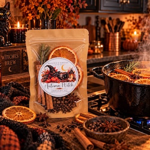 May include: A tan pouch containing a simmer pot kit with dried orange slices, cinnamon sticks, and spices. The label features the text Krystin's Krafts and Autumn Witch Simmer Pot Kit with an illustration of a witch hat and a cauldron.