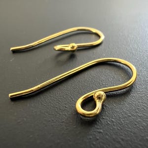 Puede incluir: Dos ganchos para pendientes de color dorado con un extremo redondeado. Los ganchos son de metal y están diseñados para usarse con pendientes.