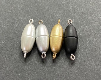Puede incluir: Cuatro cierres magnéticos de diferentes colores: blanco, plateado, dorado y negro. Cada cierre tiene forma ovalada y un pequeño bucle en cada extremo.