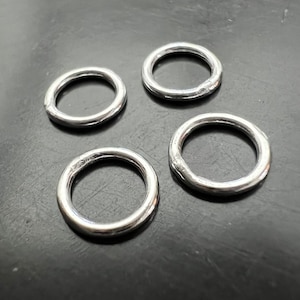 Könnte beinhalten: Vier silberne Metallringe in verschiedenen Größen. Die Ringe sind glatt und glänzend.