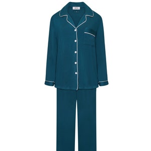 Puede incluir: Conjunto de pijama azul turquesa con ribetes blancos. La parte superior tiene un cierre de botones en la parte delantera y un bolsillo en el pecho. El pantalón tiene una pierna recta.