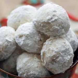May include: A bowl of white snowball cookies, dusted with powdered sugar.