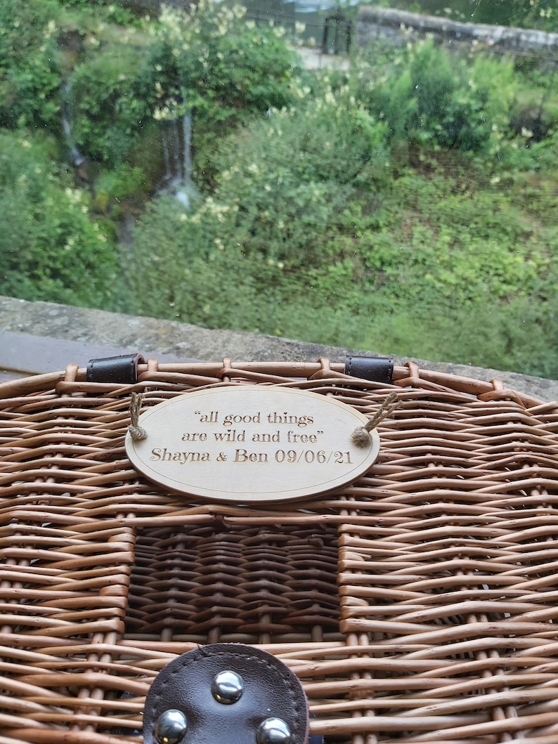 May include: A wicker picnic basket with a wooden plaque attached to the handle. The plaque reads "All good things are wild and free" with the names "Shayna & Ben" and the date "09/06/21".
