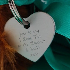 May include: A silver heart-shaped tag with the text "Just to say I Love You to the Moooon & back! xxx" hanging from a silver key ring.