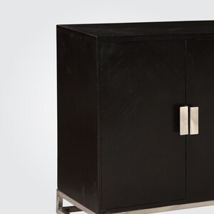 Puede incluir: Armario negro con dos puertas y tiradores plateados. El armario tiene un dise&ntilde;o moderno y est&aacute; hecho de madera.