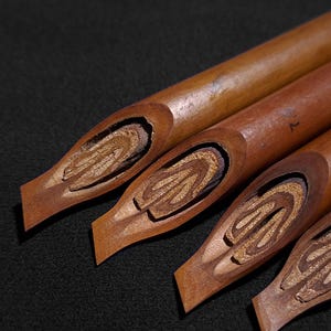 Handmade Handam Bili Arabic calligraphy pens with traditional carved bamboo nibs displayed on a dark background.