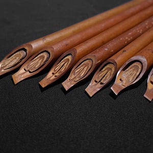 Collection of natural reed Arabic calligraphy pens with various nib widths and handcrafted finishes.
