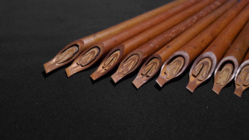 Collection of natural reed Arabic calligraphy pens with various nib widths and handcrafted finishes.