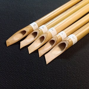 May include: Five bamboo calligraphy pens with numbered labels. The pens are arranged in a row, with the largest pen at the top and the smallest pen at the bottom. The numbers on the labels are 8, 9, 10, 11, and 12.