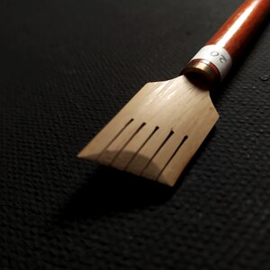 May include: A wooden calligraphy pen with a brown handle and a metal nib. The pen has a white label with the number "20" on it.