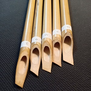 May include: Five bamboo calligraphy pens with different sized nibs. The nibs are labeled with numbers 8, 6, 10, 11, and 12.