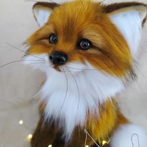 May include: A plush fox toy with a detailed, realistic design. The fox features a vibrant orange and brown fur coat, white chest and ear accents, and a black nose. It has long whiskers and expressive eyes, giving it a lifelike appearance. The toy is a charming decorative item.