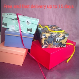 May include: Four gift boxes stacked on top of each other. The top box is green with a white and black animal print. The second box is blue with a gold trim. The third box is orange. The bottom box is red. The boxes are tied with a red ribbon and a yellow ribbon.