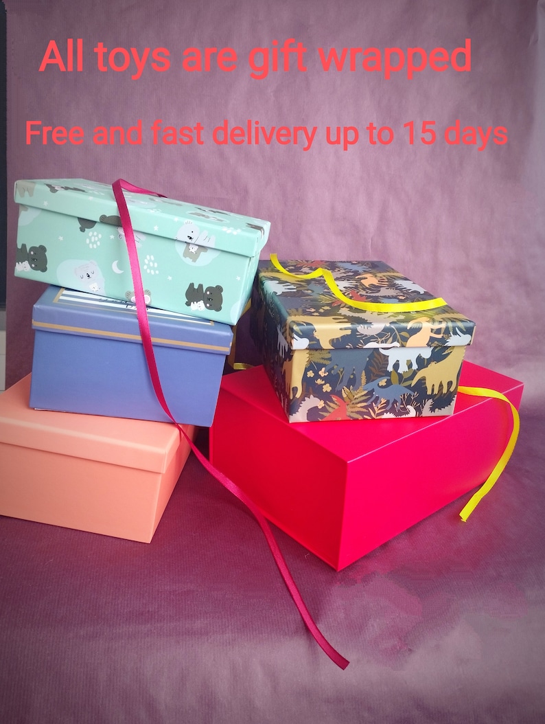 May include: Four gift boxes stacked on top of each other. The top box is green with a white and black animal print. The second box is blue with a gold trim. The third box is orange. The bottom box is red. The boxes are tied with a red ribbon and a yellow ribbon.